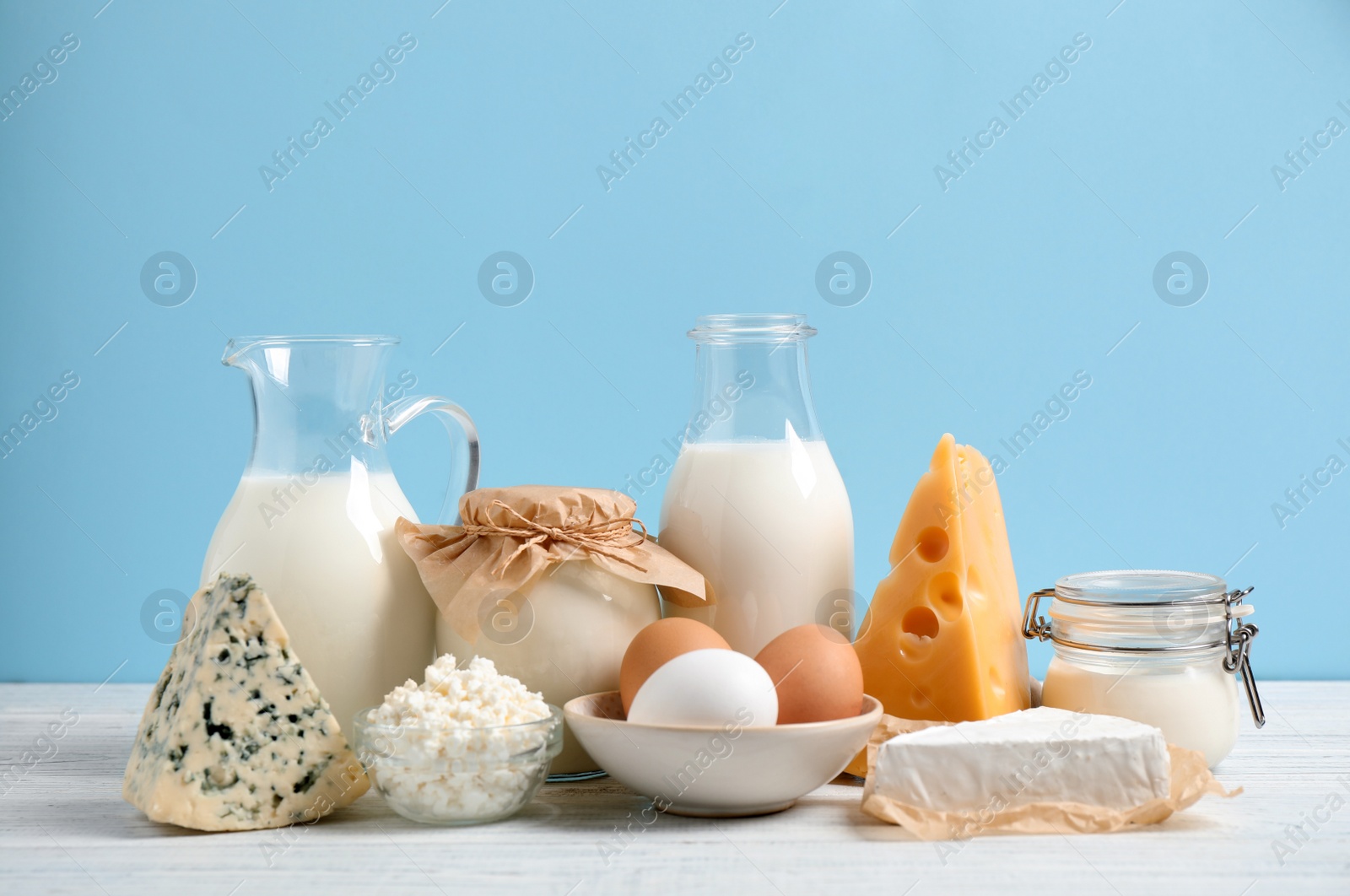 Photo of Different dairy products on white table against blue background