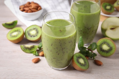 Delicious kiwi smoothie and ingredients on white wooden table