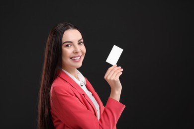Photo of Happy woman holding blank business card on black background. Space for text