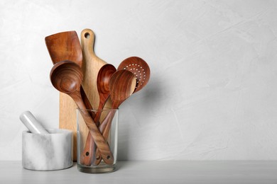 Photo of Set of kitchen utensils, board and mortar with pestle on white wooden table. Space for text