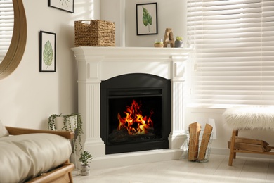 Bright living room interior with artificial fireplace and firewood in basket