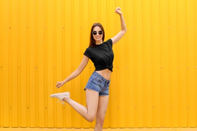 Young woman wearing black t-shirt near color wall on street