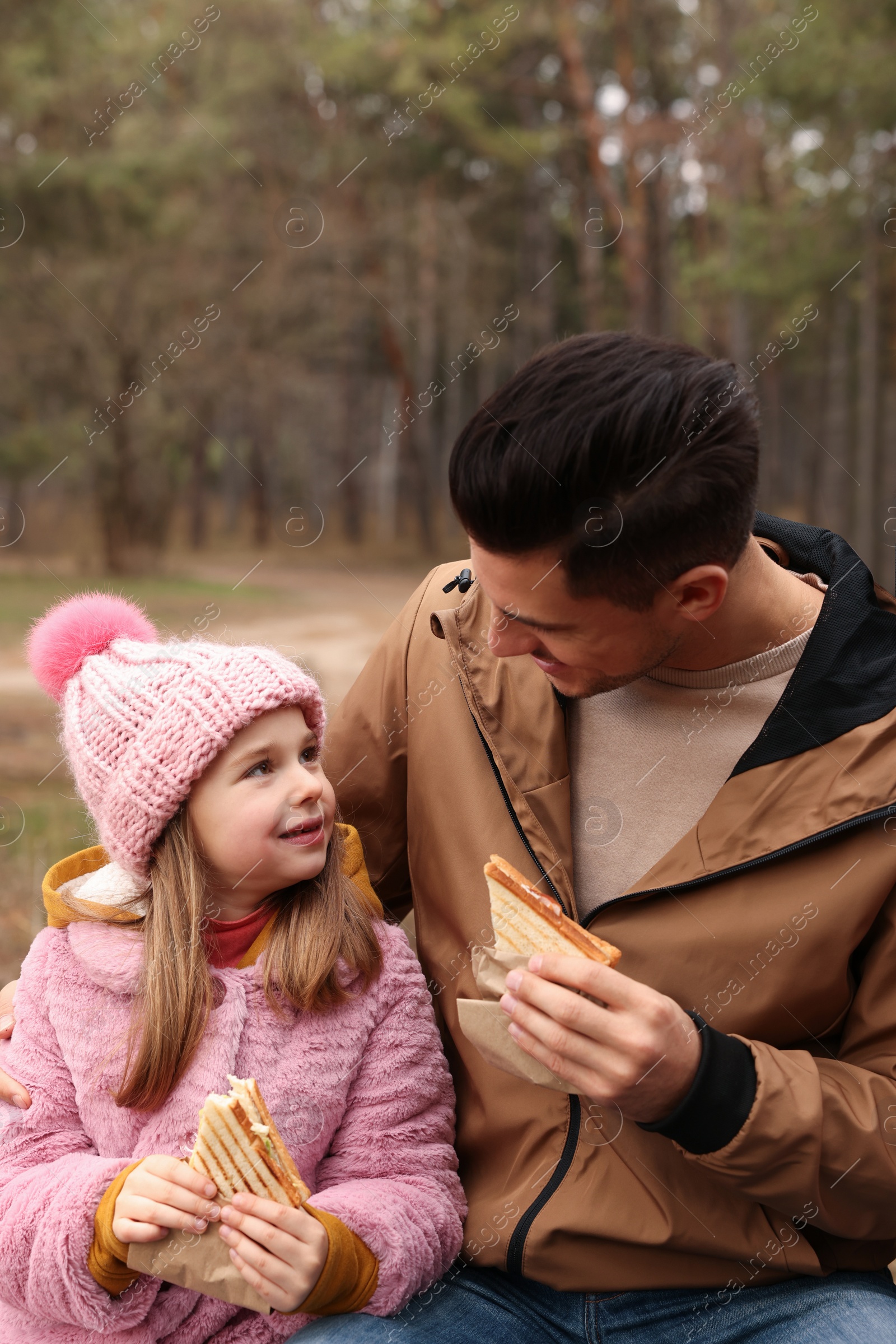 Photo of Happy family with sandwiches spending time together in forest