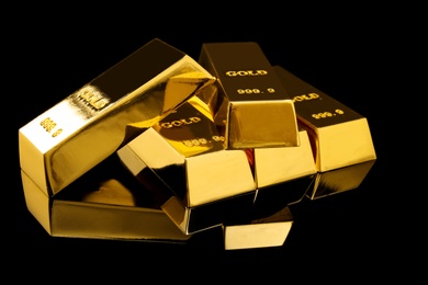 Photo of Many shiny gold bars on black background