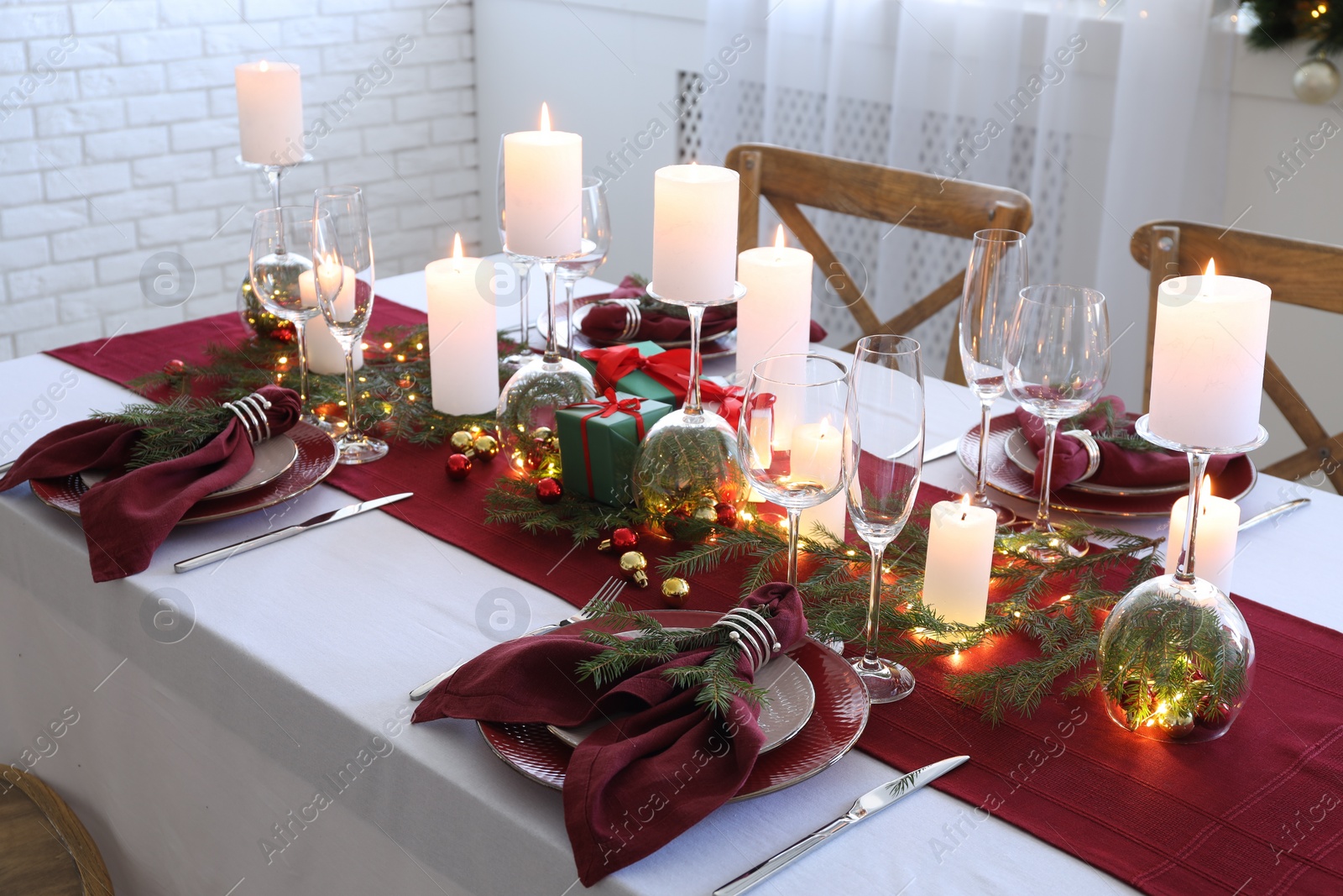 Photo of Christmas table setting with burning candles and festive decor