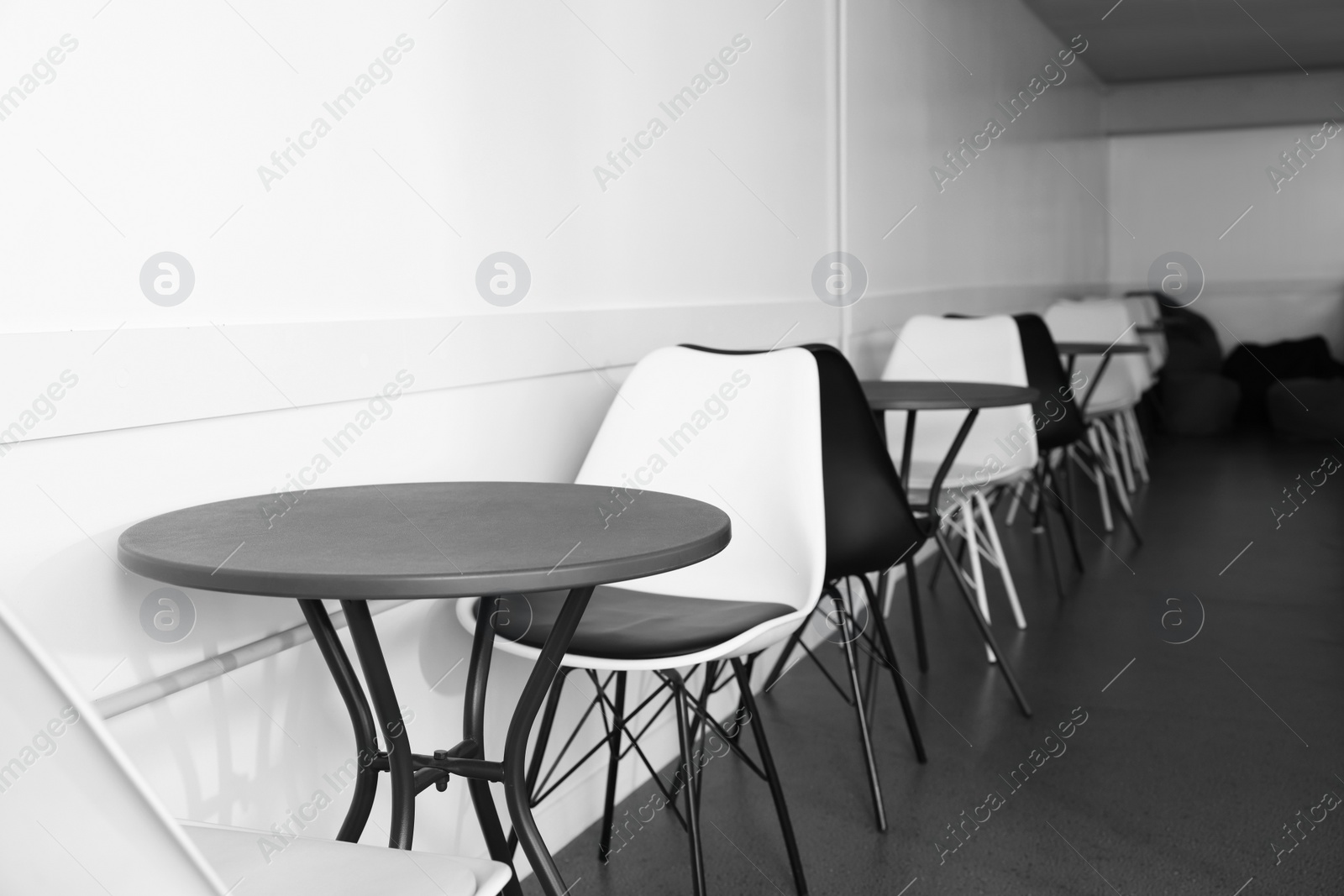 Photo of Hostel dining room interior with tables and chairs along white wall