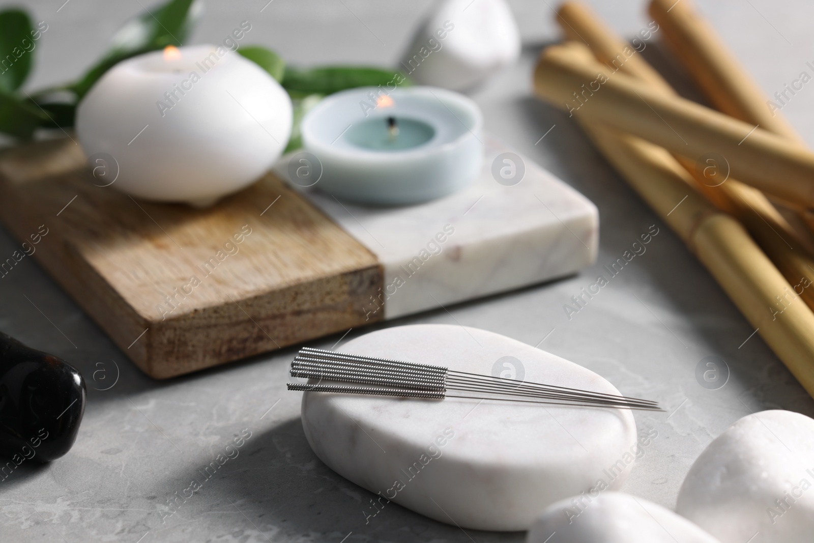 Photo of Stone with acupuncture needles on light grey marble table