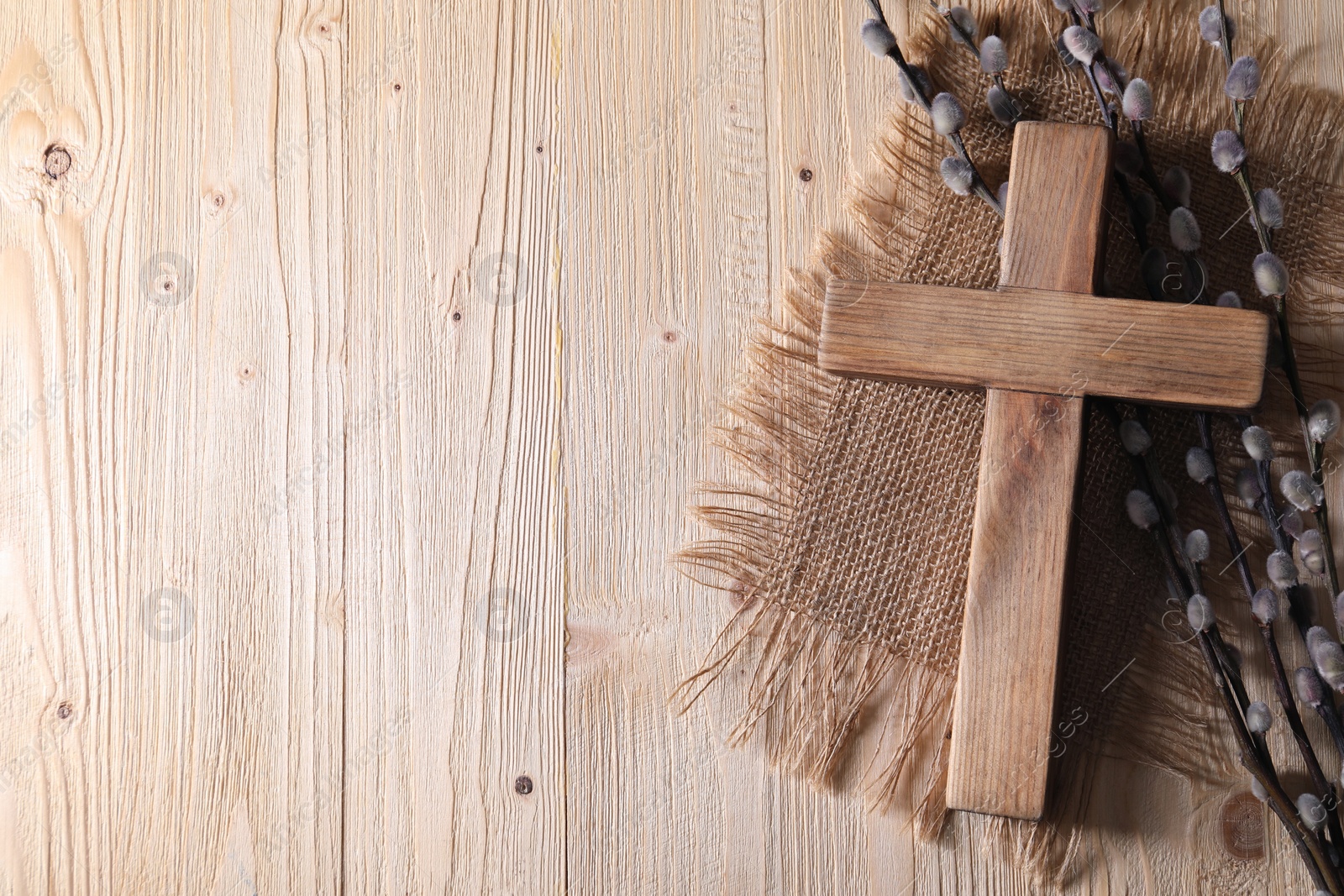 Photo of Cross and willow branches on wooden background, flat lay. Space for text