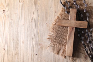 Photo of Cross and willow branches on wooden background, flat lay. Space for text