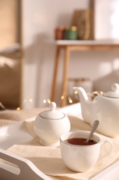Photo of Ceramic tea set on white tray in room
