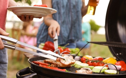 Young people having barbecue with modern grill outdoors