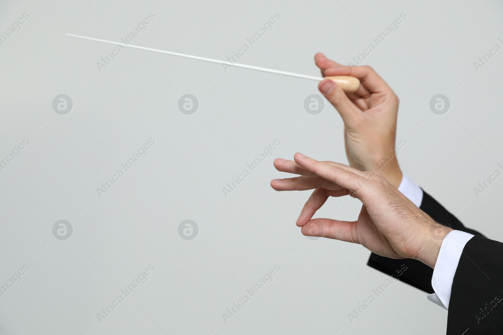 Photo of Professional conductor with baton on light grey background, closeup. Space for text