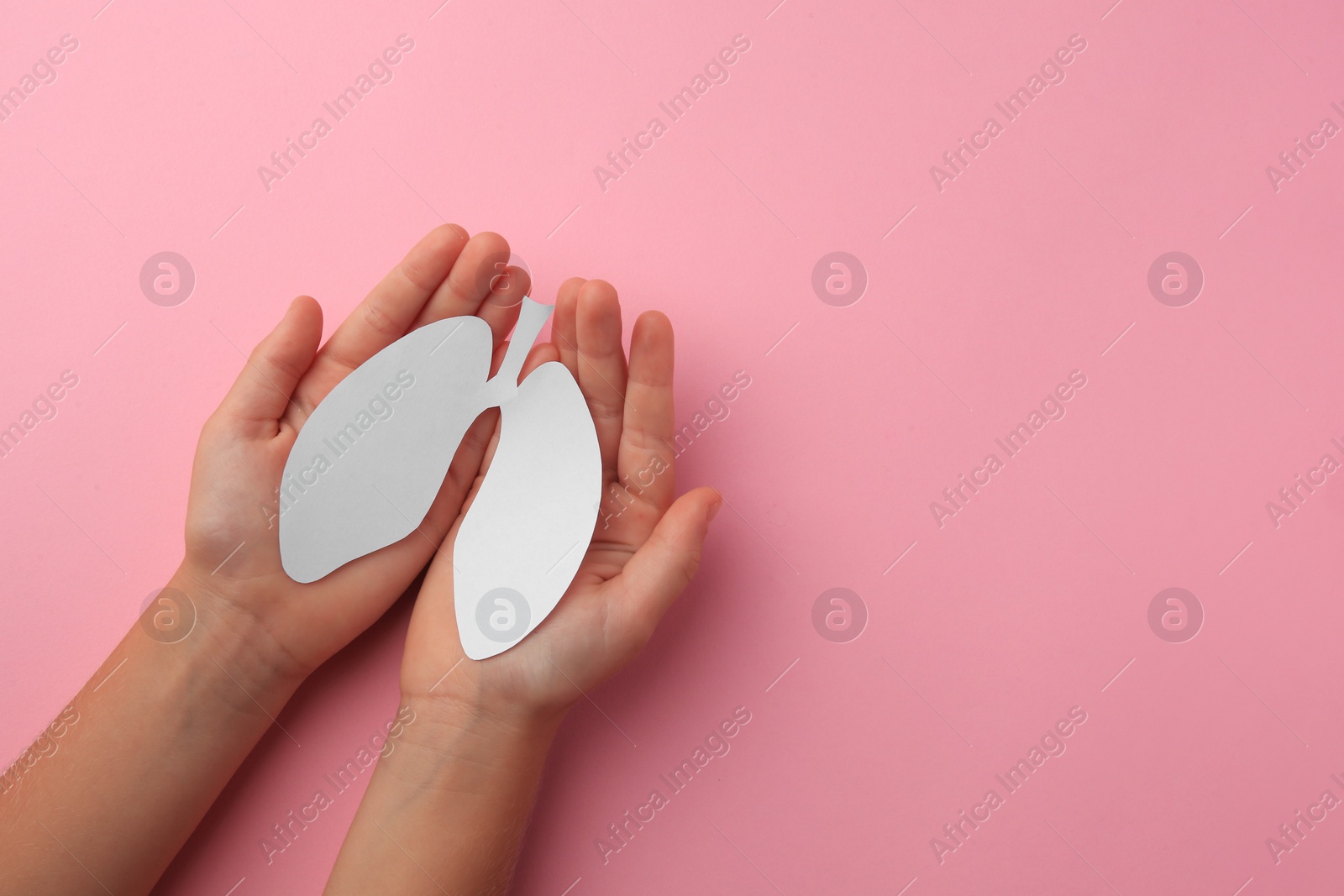 Photo of Child holding paper human lungs on pink background, top view. Space for text