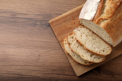Photo of Cut tasty wheat sodawater bread on wooden table, top view. Space for text