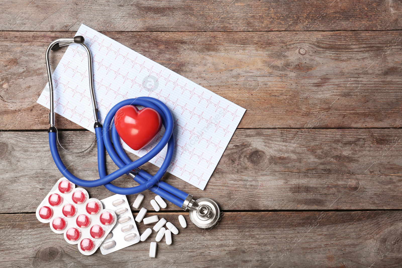 Photo of Stethoscope, cardiogram and pills on wooden background. Cardiology service