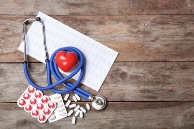 Photo of Stethoscope, cardiogram and pills on wooden background. Cardiology service