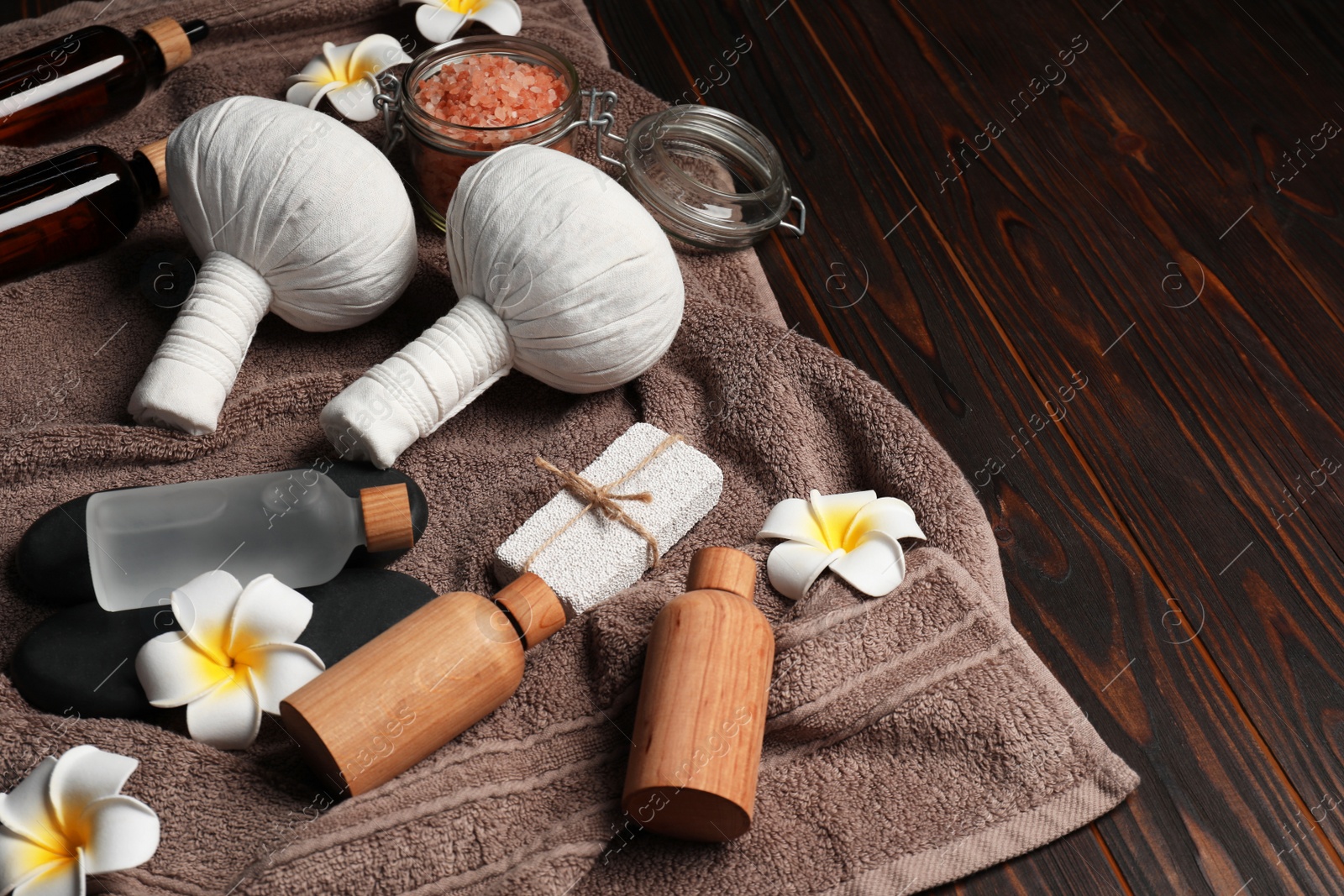 Photo of Herbal massage bags and other spa products on wooden table, space for text