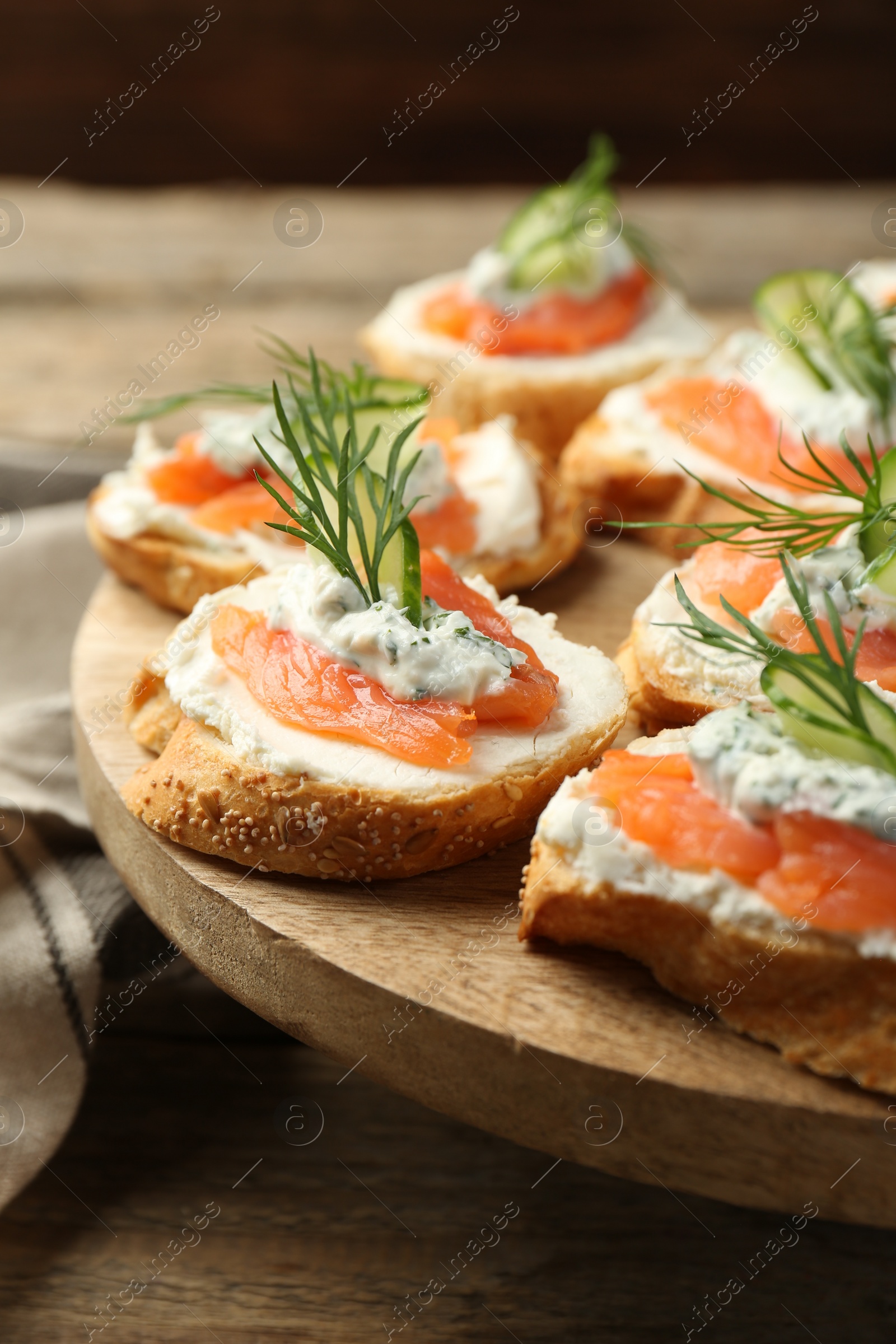 Photo of Tasty canapes with salmon, cucumber, cream cheese and dill on wooden table