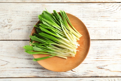 Photo of Plate with wild garlic or ramson on wooden table, top view