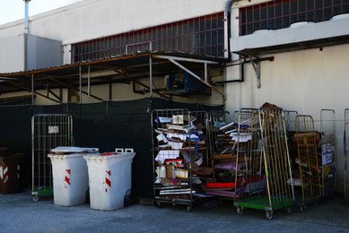 Photo of Plastic trash bins and bundles of cardboard near industrial building