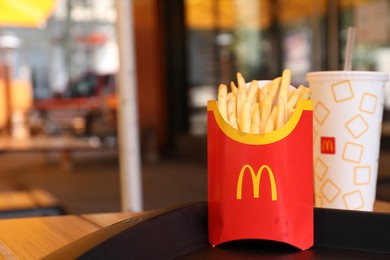 MYKOLAIV, UKRAINE - AUGUST 11, 2021: Big portion of McDonald's French fries and drink on table in cafe. Space for text