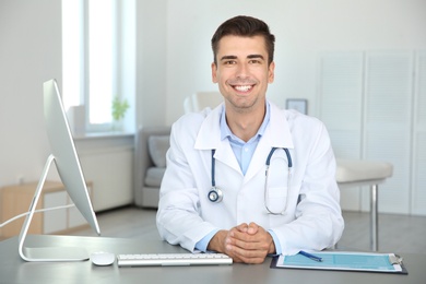 Portrait of young doctor at table in hospital