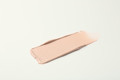 Photo of Stroke of pink correcting concealer on white background