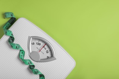 Weight loss concept. Scales and measuring tape on green background, top view. Space for text