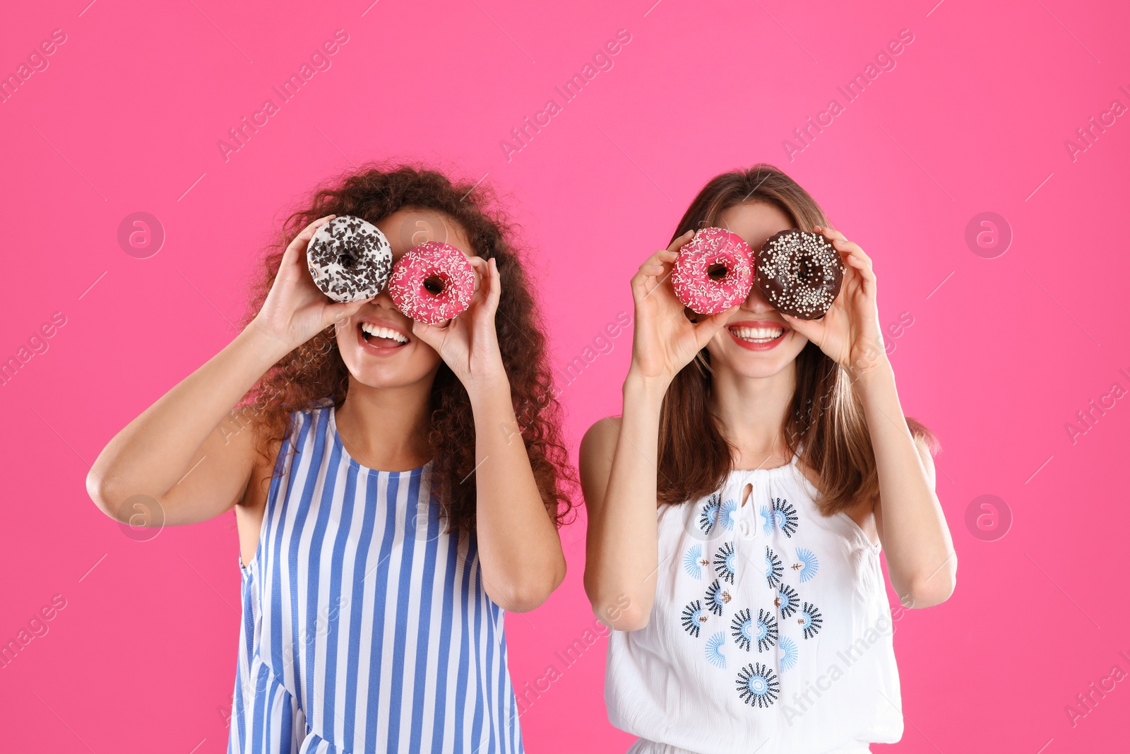 Photo of Beautiful young women with donuts on pink background