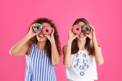 Beautiful young women with donuts on pink background