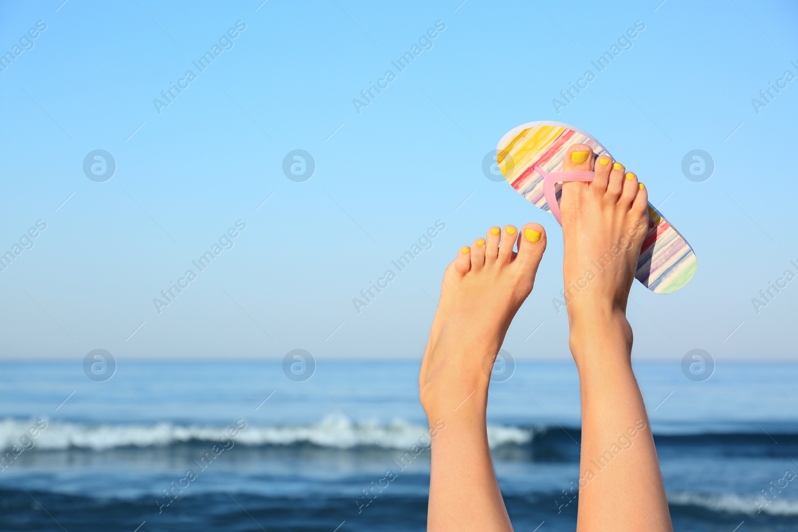 Photo of Closeup of woman wearing flip flop near sea, space for text. Beach accessories