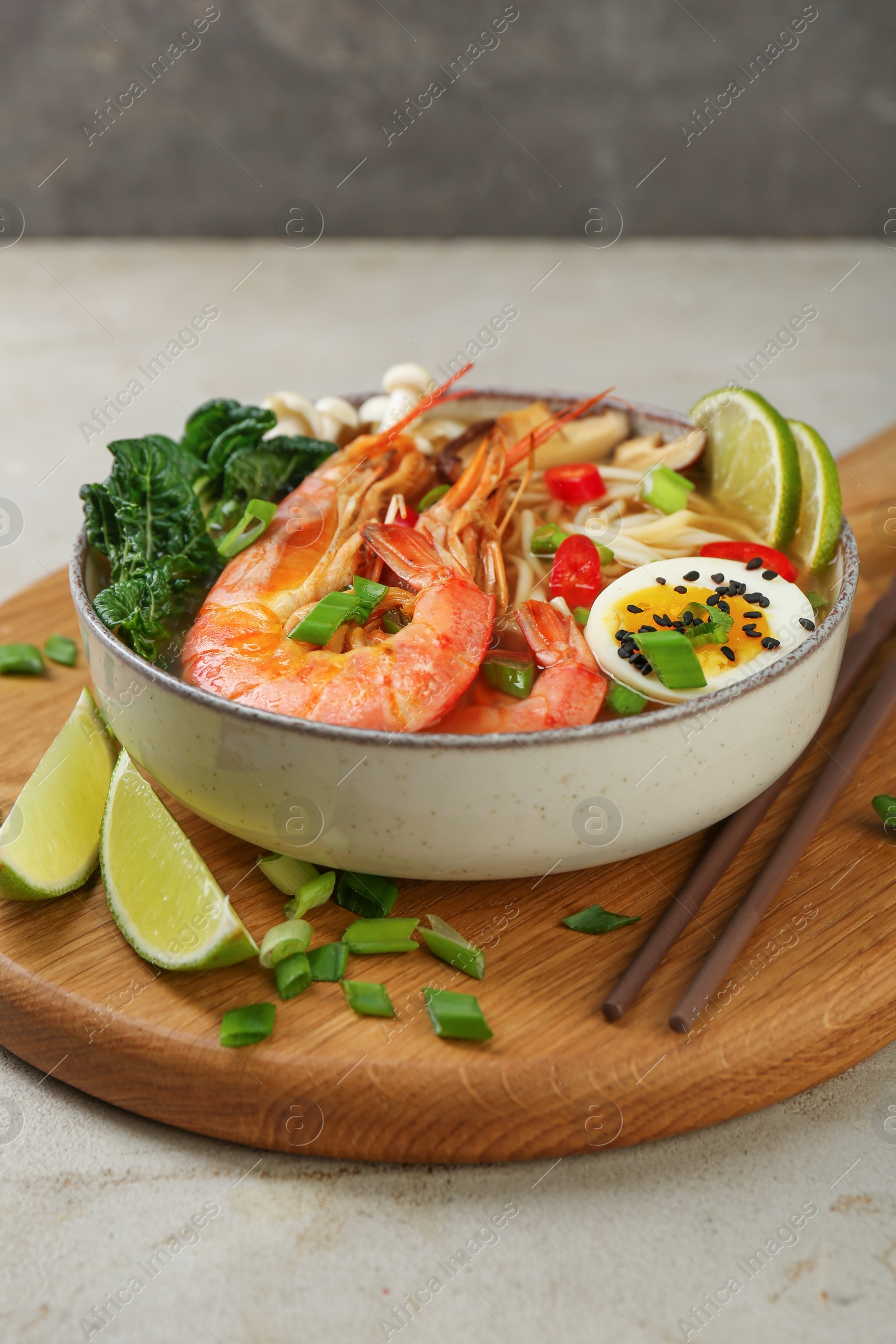 Photo of Delicious ramen with shrimps, egg in bowl and chopsticks on light textured table. Noodle soup