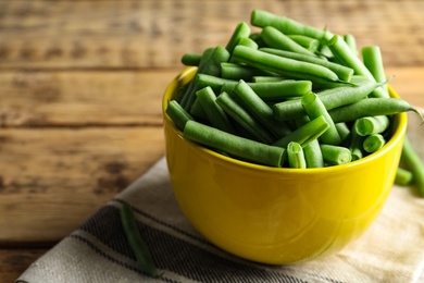 Photo of Fresh green beans in bowl on wooden table, closeup. Space for text