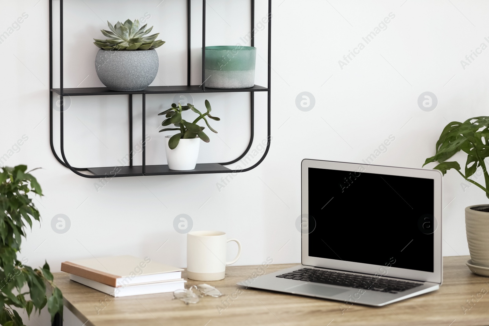 Photo of Comfortable workplace with modern laptop on wooden table in room. Interior design