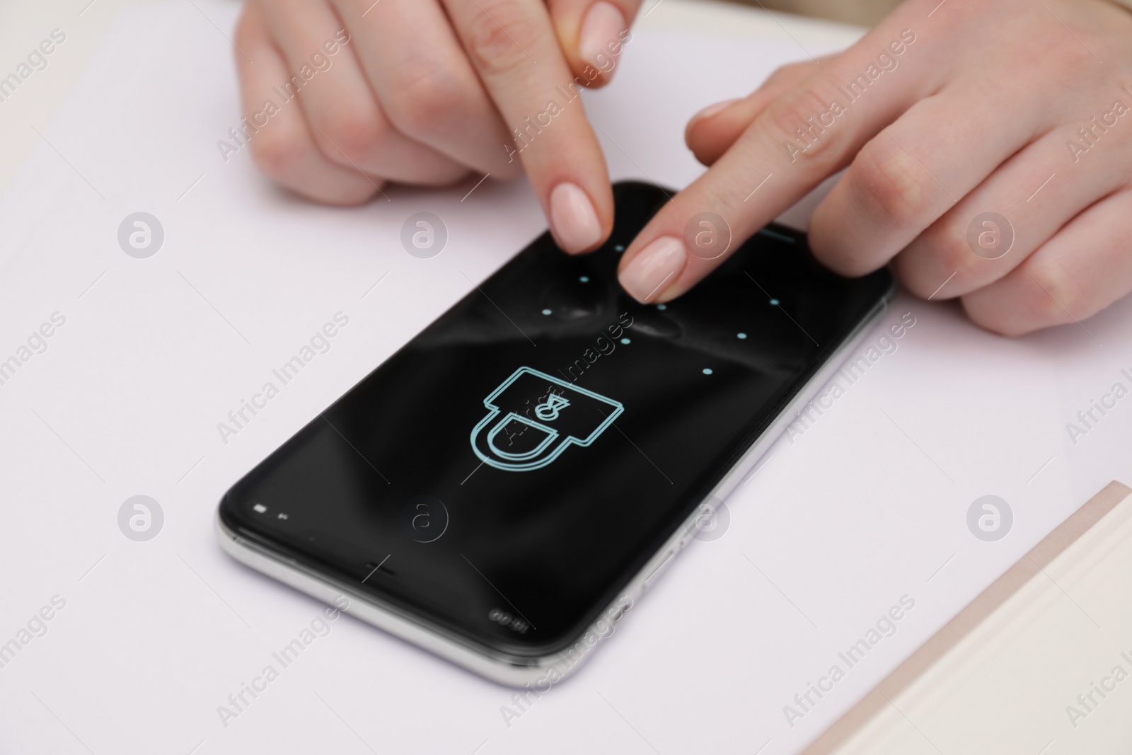 Photo of Woman unlocking smartphone with blocked screen at white table, closeup