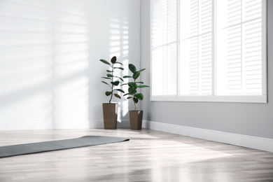 Photo of Unrolled grey yoga mat on floor in room