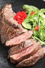 Photo of Pieces of delicious grilled beef meat and greens on plate, closeup