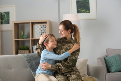 Photo of Woman in military uniform with her little son on sofa at home