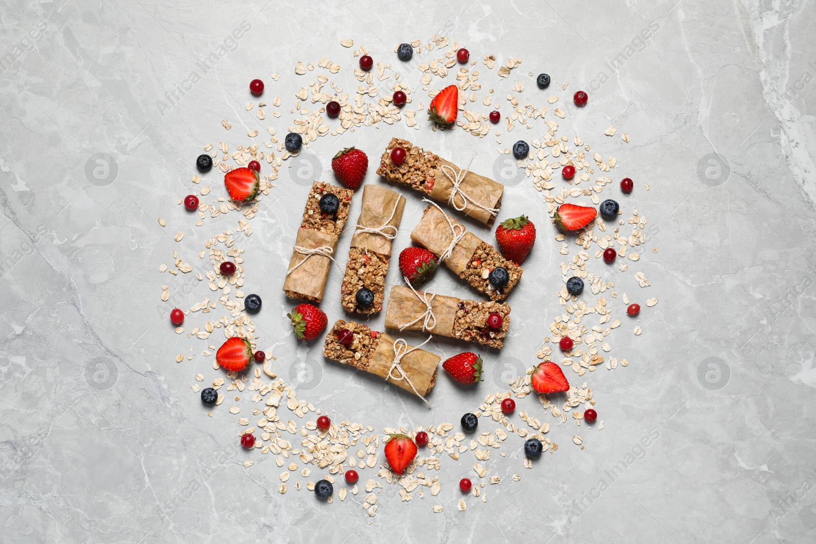 Photo of Tasty granola bars and ingredients on light grey marble table, flat lay