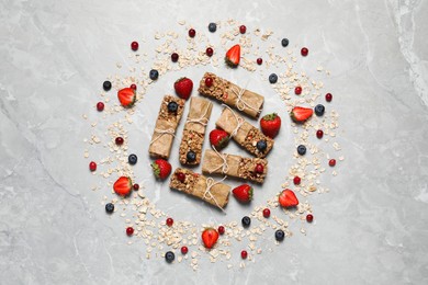 Photo of Tasty granola bars and ingredients on light grey marble table, flat lay