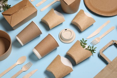 Eco friendly food packaging. Paper containers, tableware and green twigs on light blue background