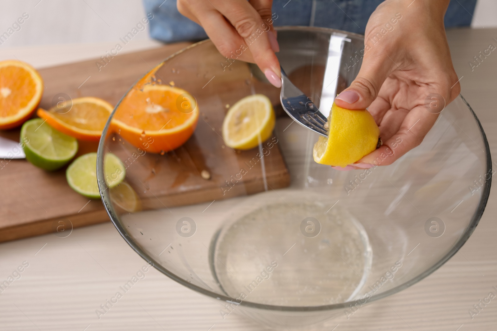 Photo of Young woman squeezing juice in bowl for lemonade on table, closeup. Natural detox drink