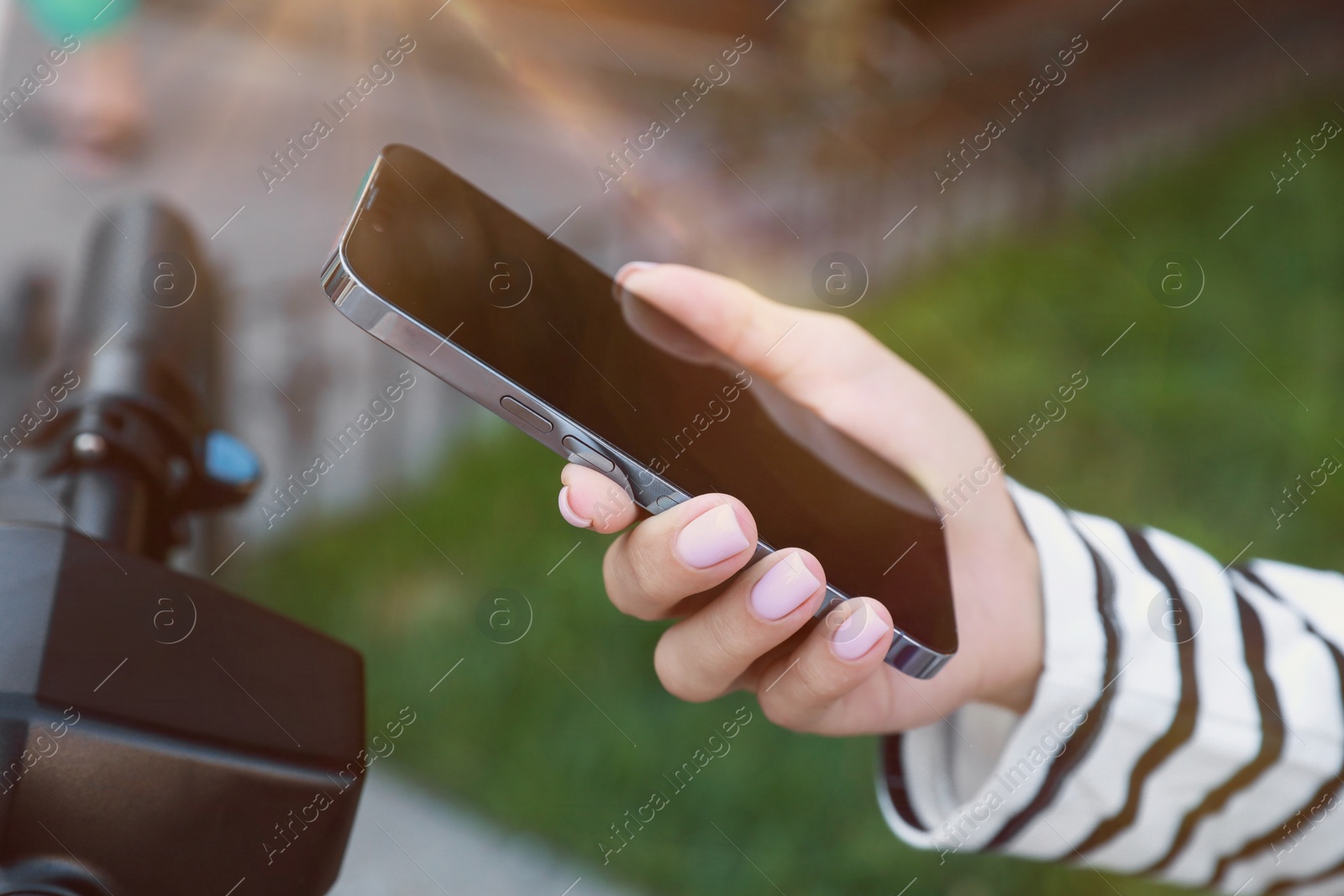 Photo of Woman using smartphone to pay and unblock electric kick scooter outdoors, closeup