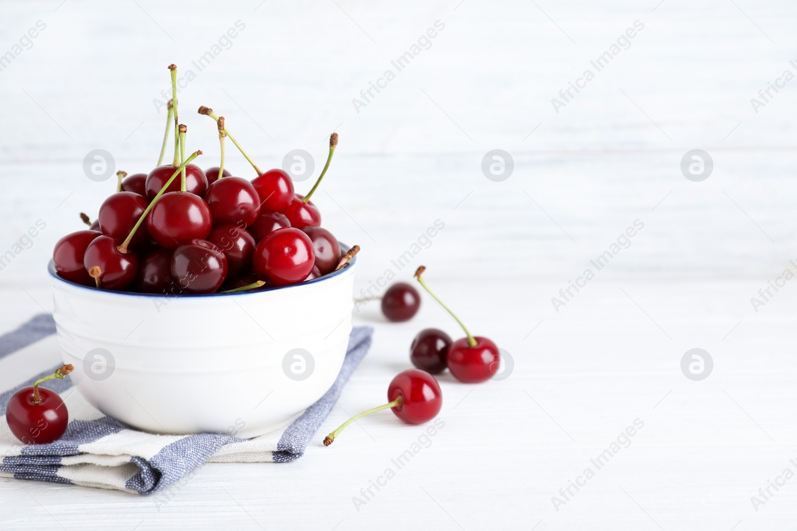 Photo of Sweet juicy cherries on white wooden table. Space for text