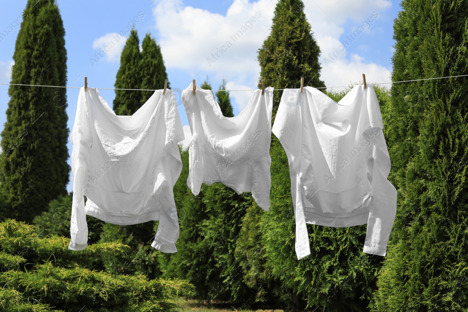 Photo of Clean clothes hanging on washing line in garden. Drying laundry