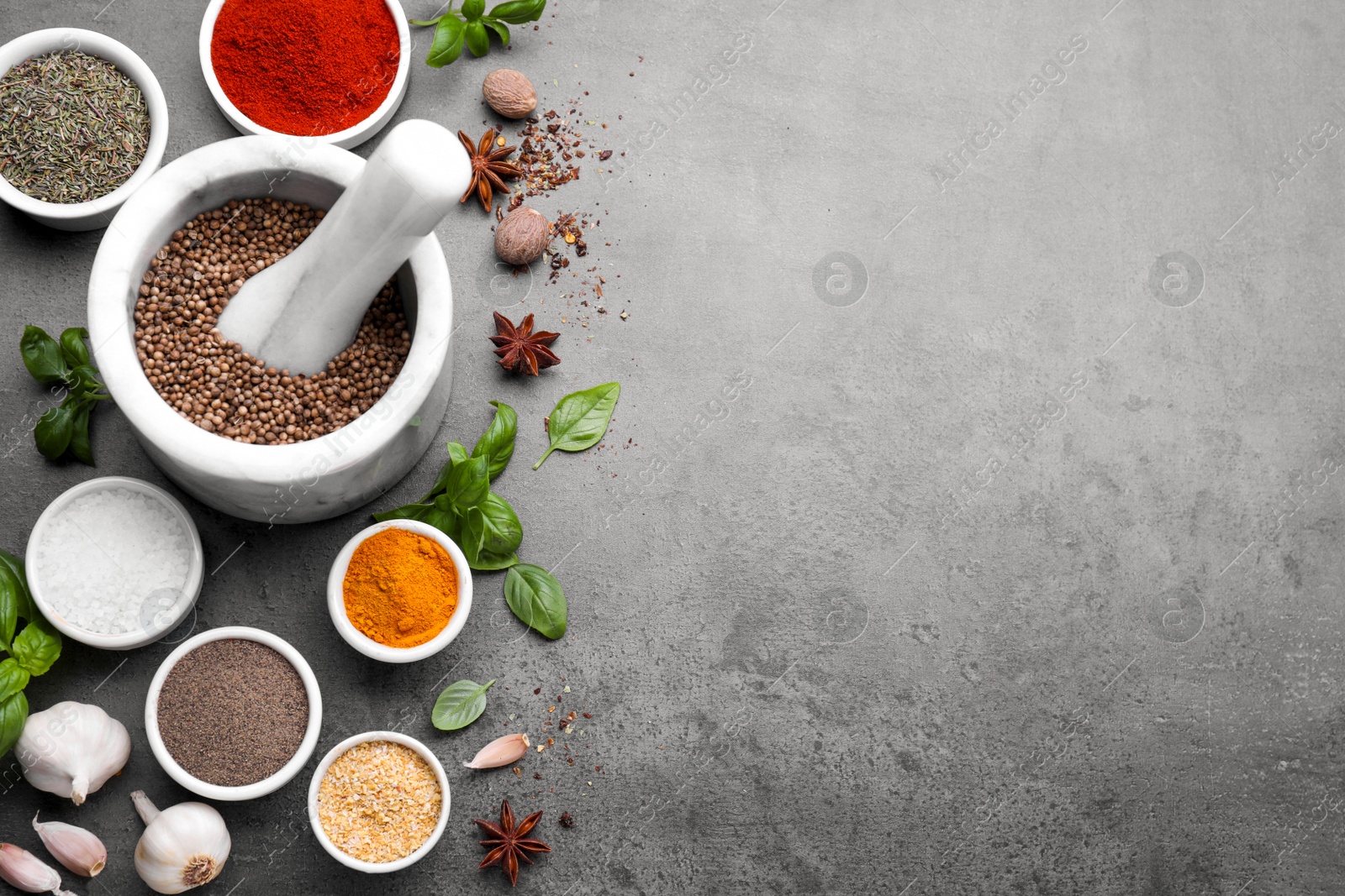 Photo of Mortar with different spices on grey table, flat lay. Space for text