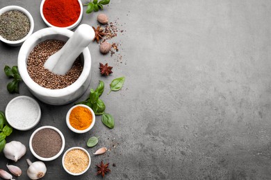 Mortar with different spices on grey table, flat lay. Space for text