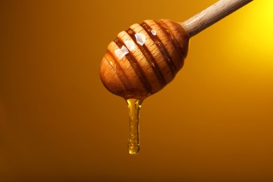 Pouring honey from dipper against golden background