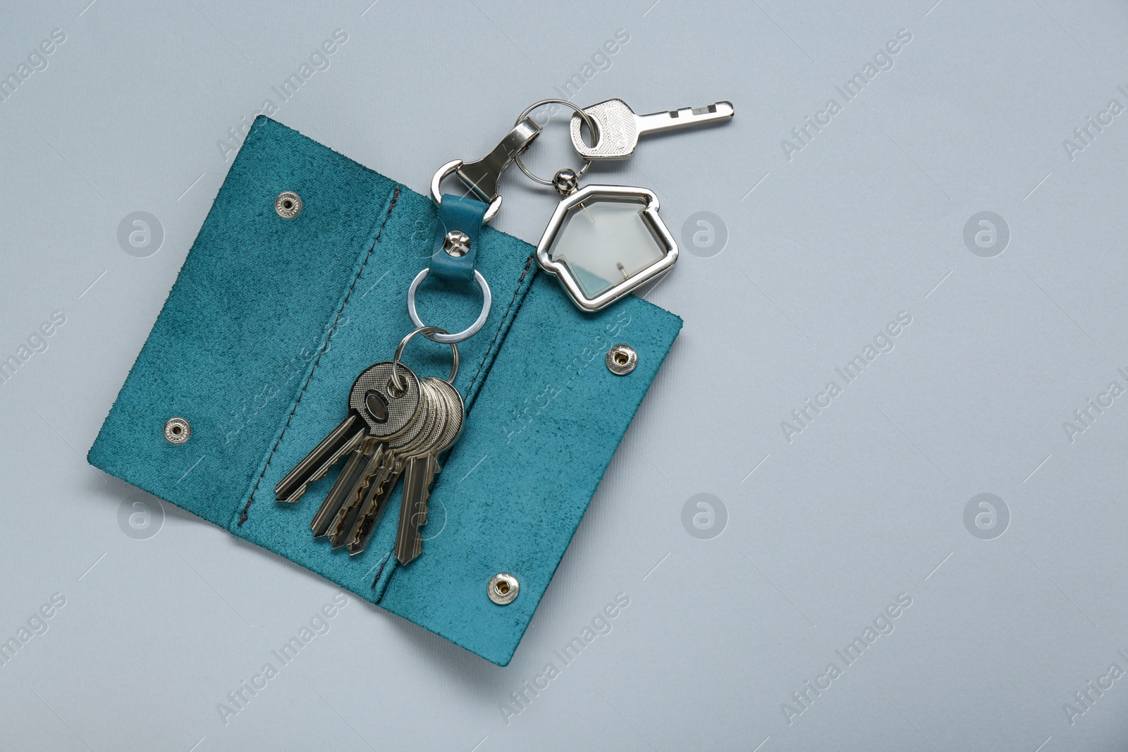Photo of Open leather holder with keys on light grey background, top view. Space for text