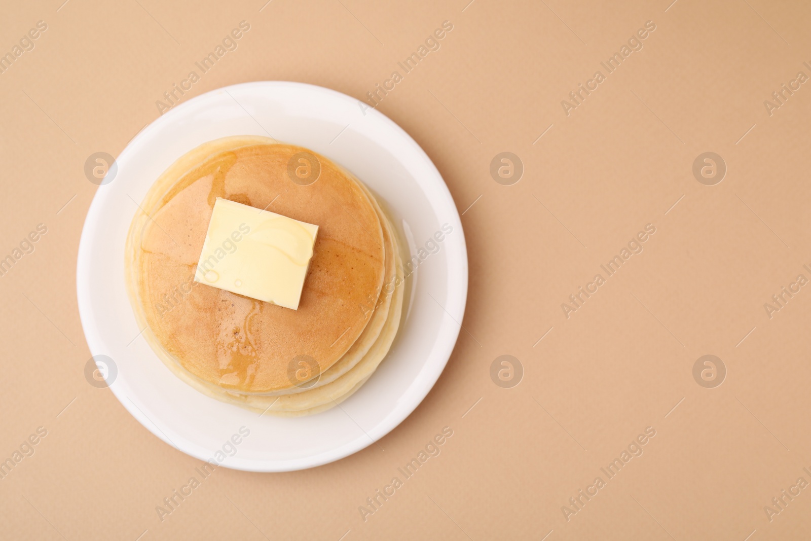 Photo of Delicious pancakes with butter and honey on beige background, top view. Space for text